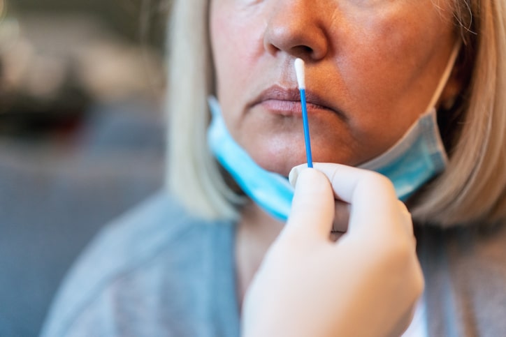 Doctor's hands in protection gloves taking swab from his patient's nose for the coronavirus test