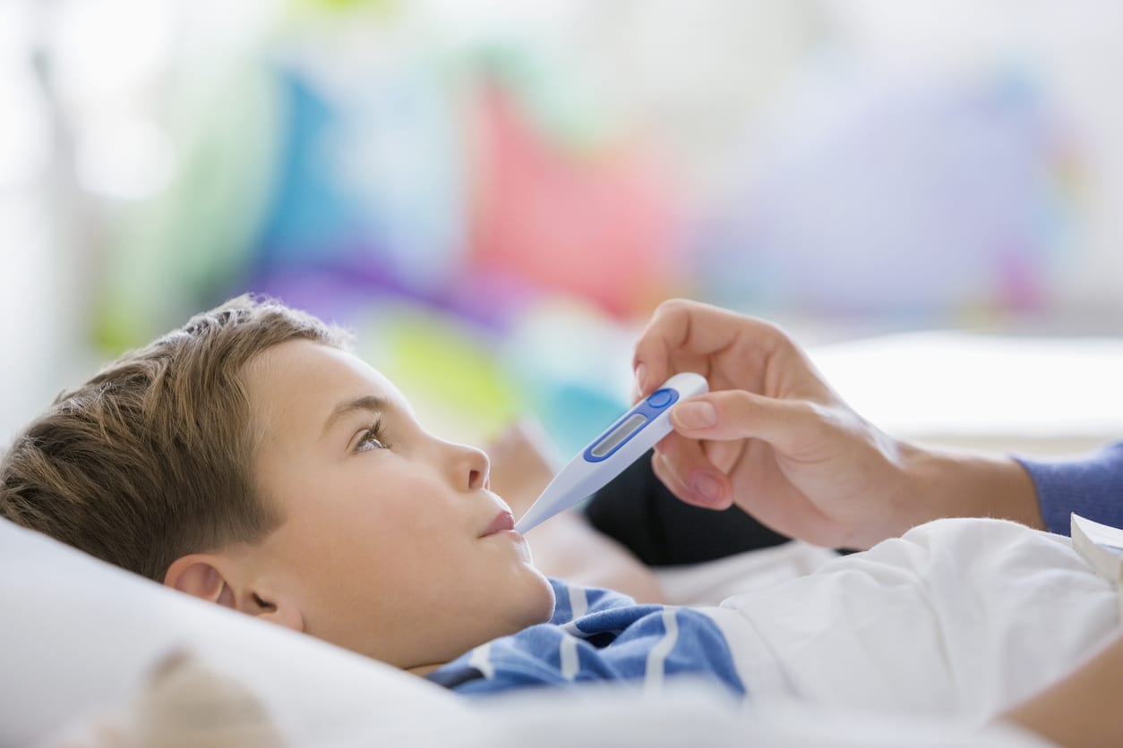 Little boy having body temperature taken by mom.