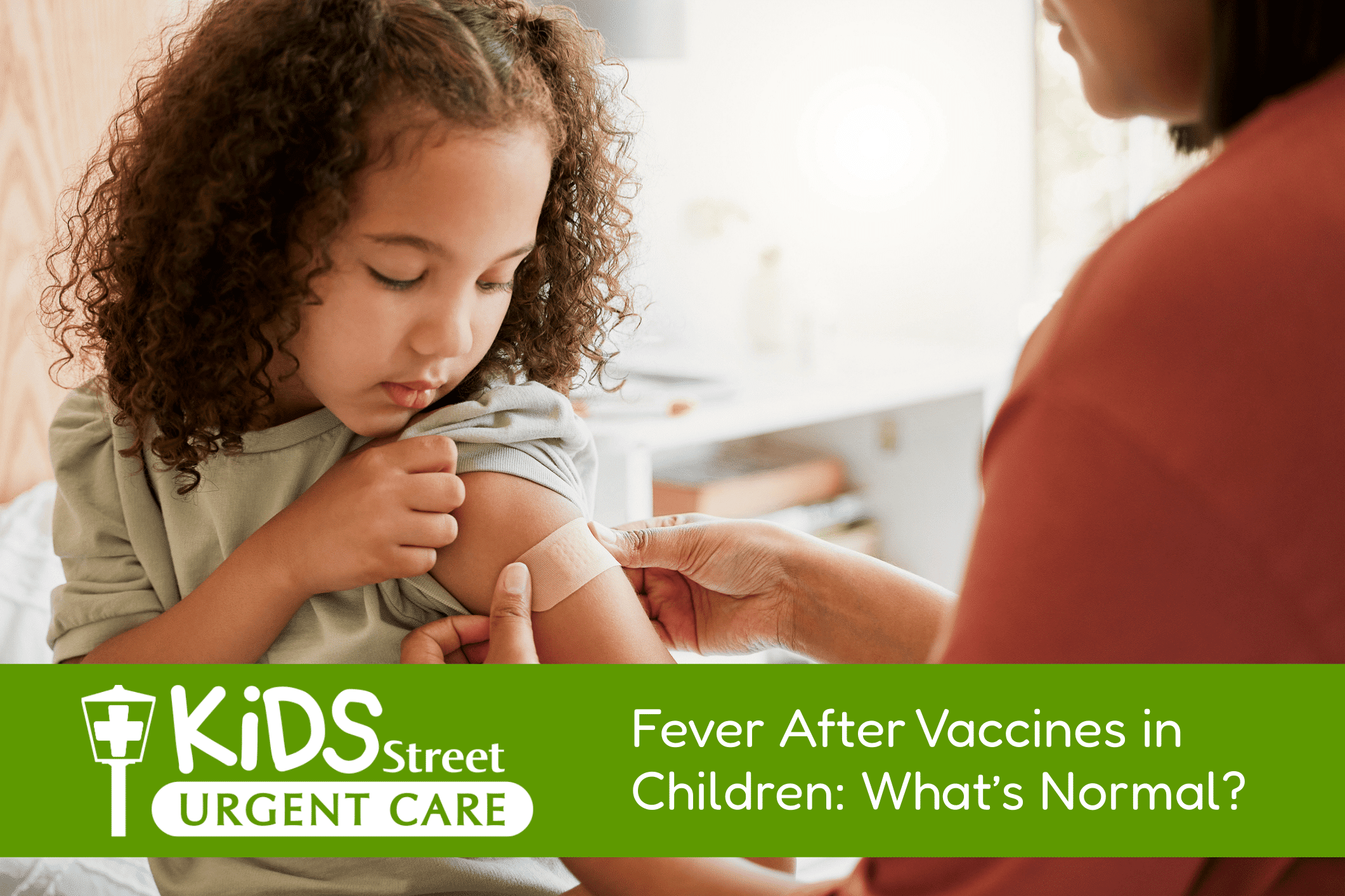 Little girl getting a bandaid on her arm after a vaccine.